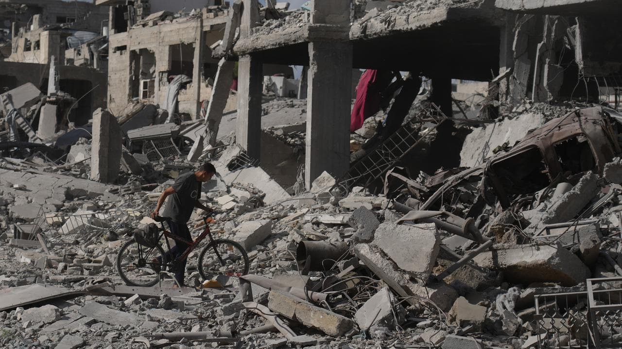 A man pushes his bicycle through rubble in Gaza City,