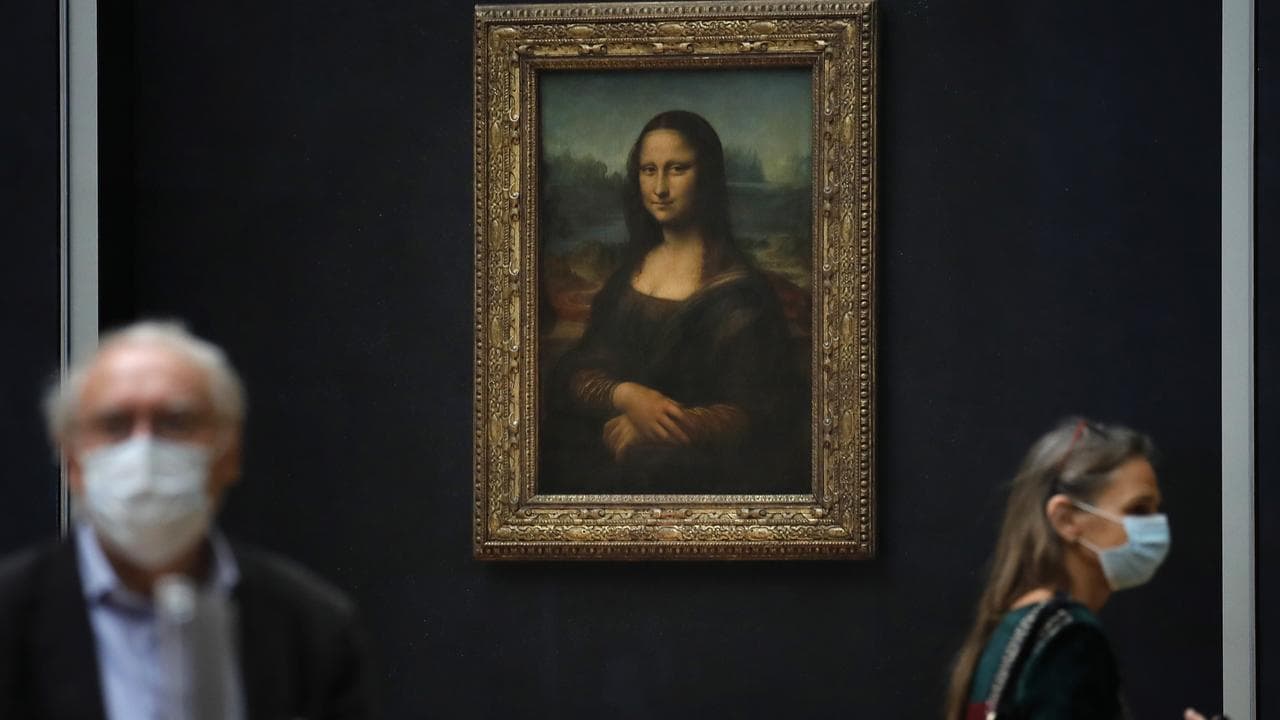 Journalists walk past Leonardo da Vinci's Mona Lisa