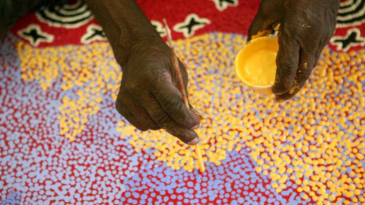 Aboriginal artist Paddy Stewart works on a dot painting