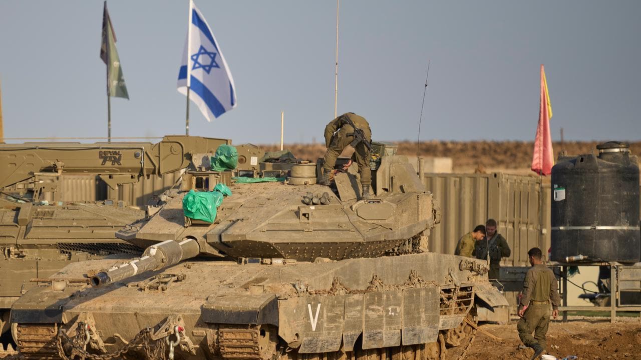 Israeli soldiers work on tanks on the border with Gaza Strip