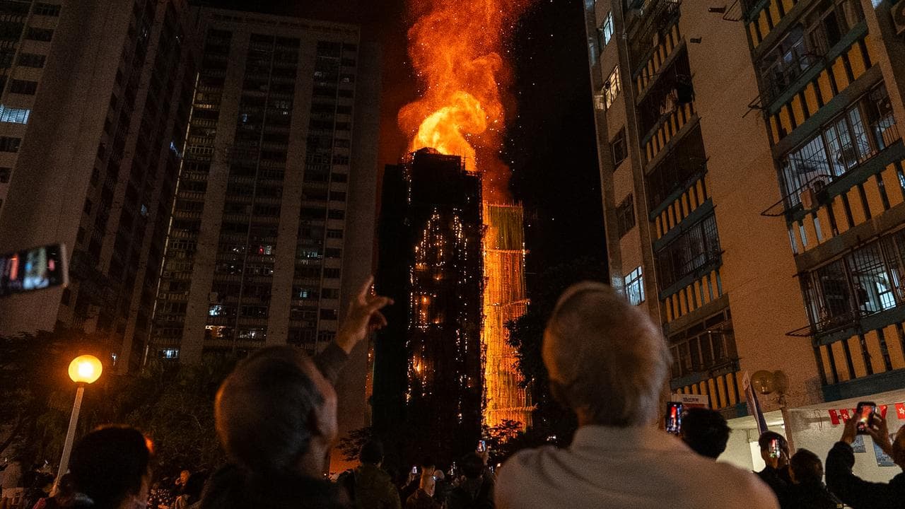 People look at flames engulfing a building in Hong Kong