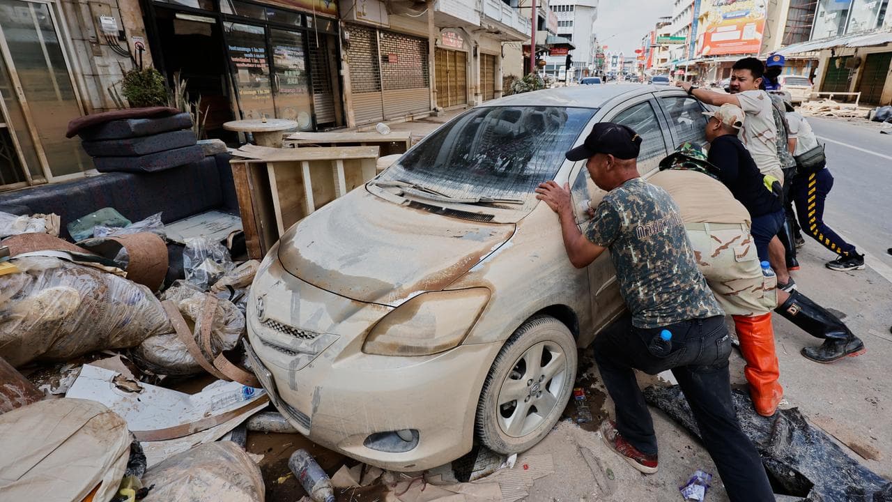 Peoples move a car damaged from floods in Songkhla province, Thailand