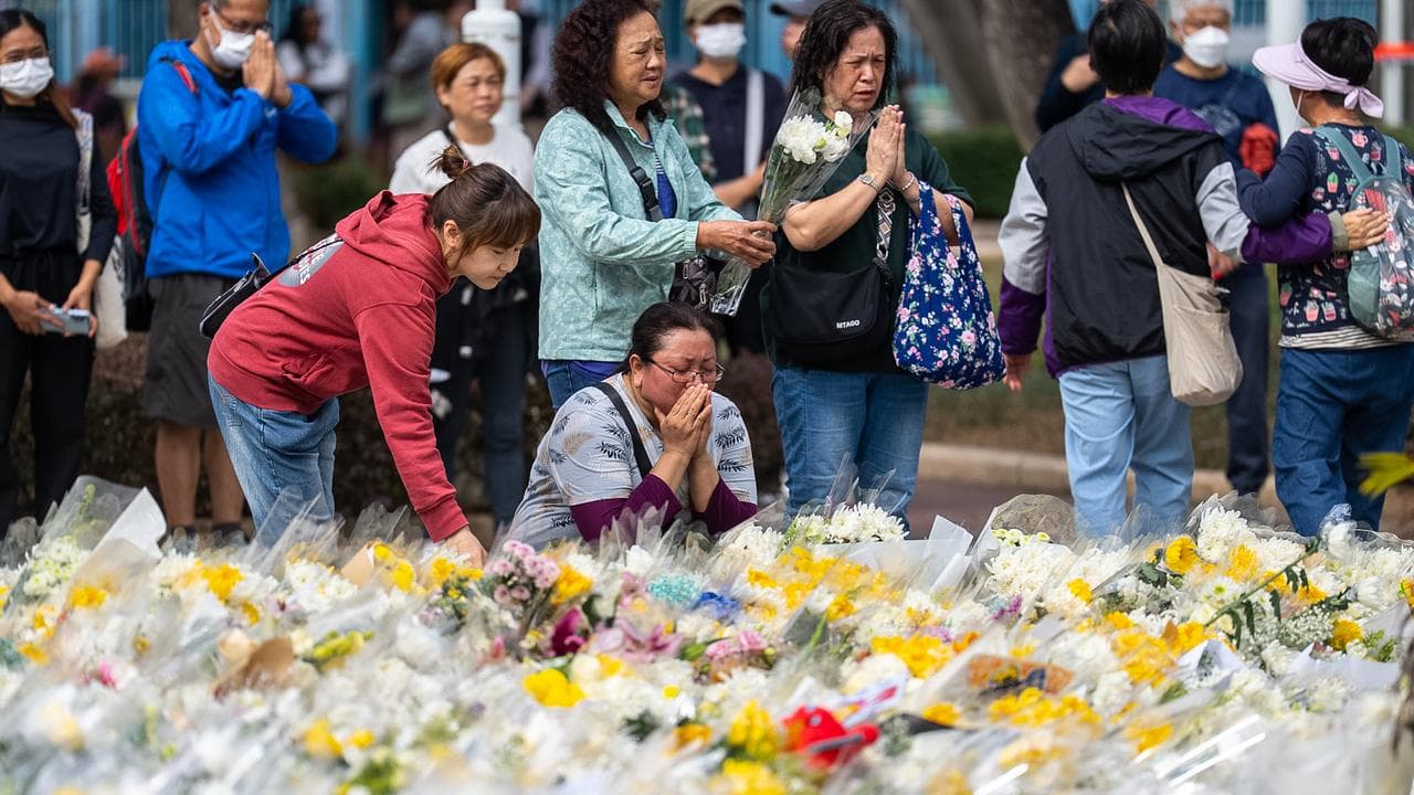 People offer flowers for the victims of the Wang Fuk Court fire