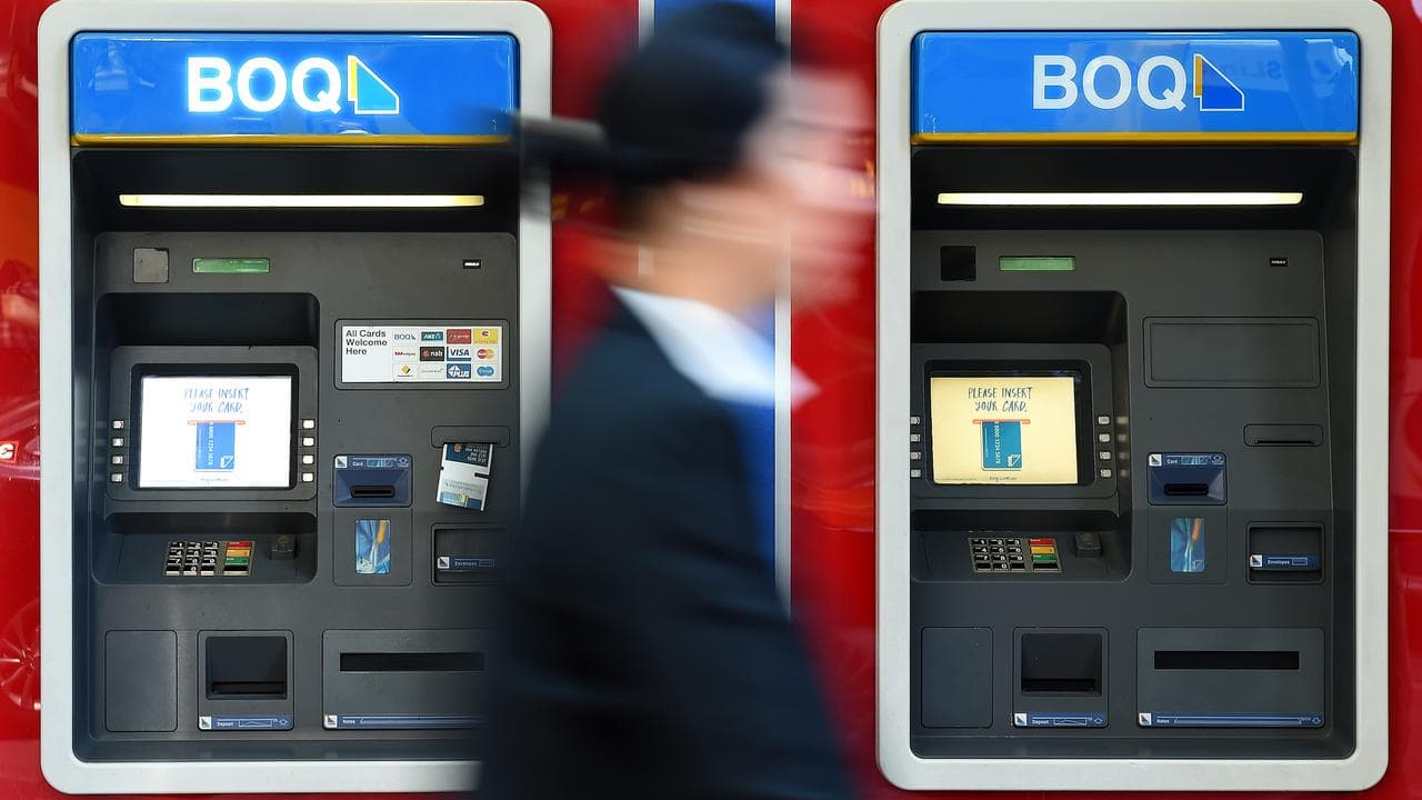 A person walks past Bank of Queensland ATMS