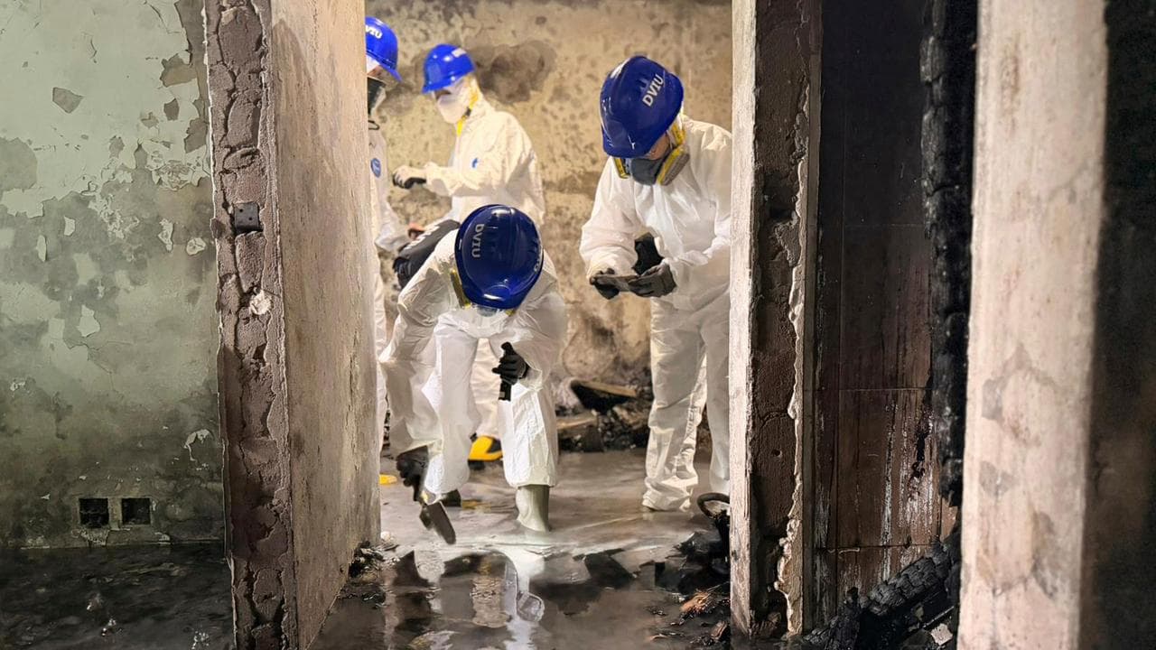Police work in an apartment at the burnt-out Wang Fuk Court complex