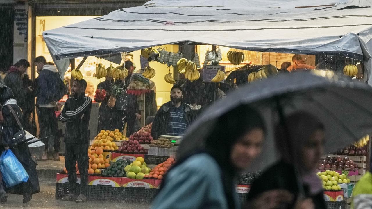 Pedestrians take cover from the rain in Gaza City