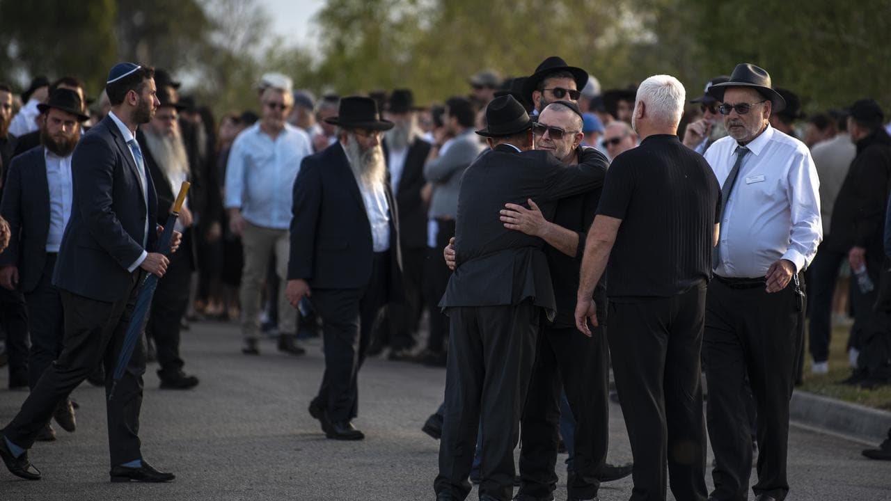 Mourners embrace after laying Reuven Morrison to rest in Melbourne