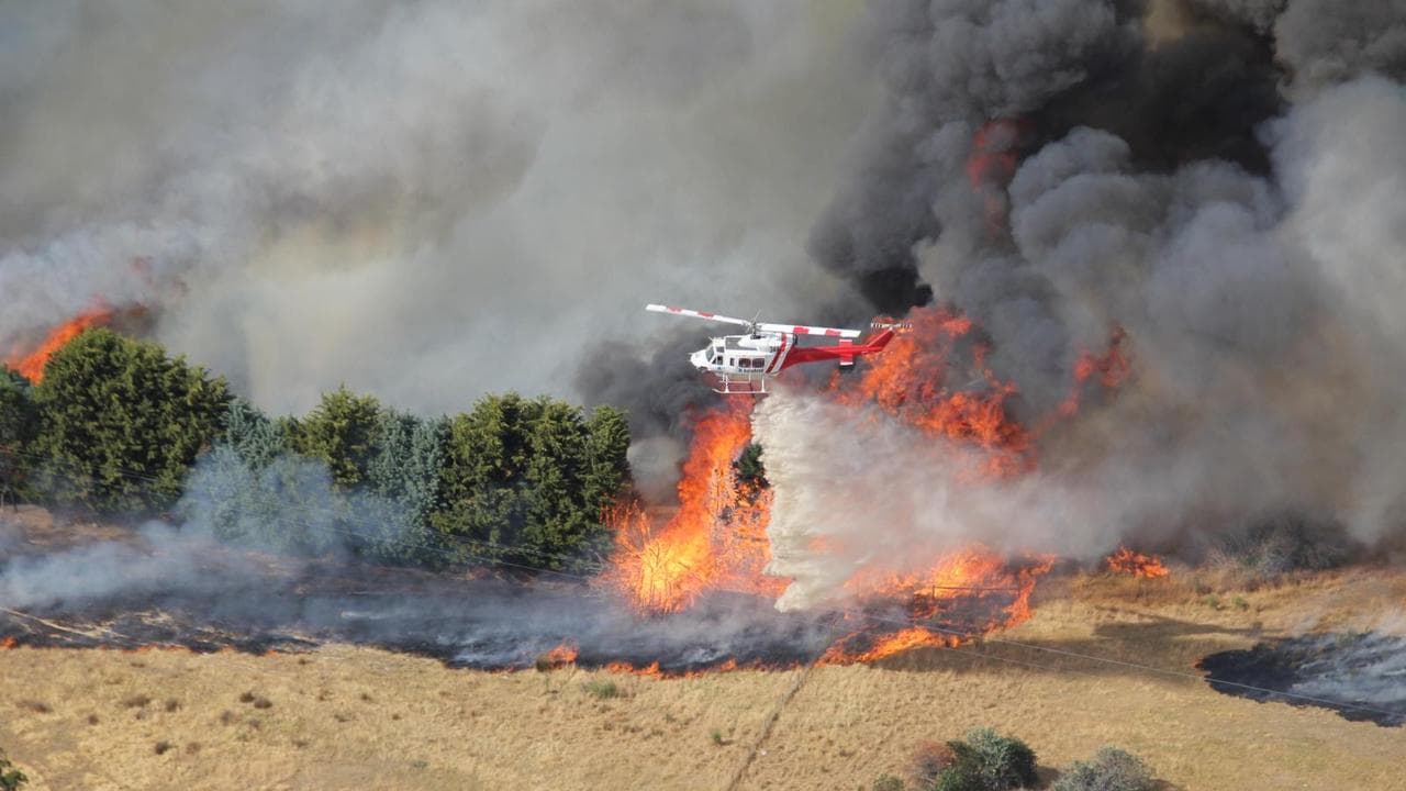 A firefighting helicopter dousing flames at a bushfire in Longwood