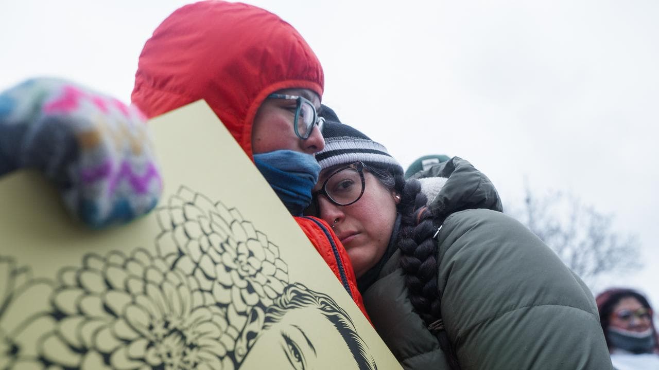 People embrace at the memorial for Renee Good
