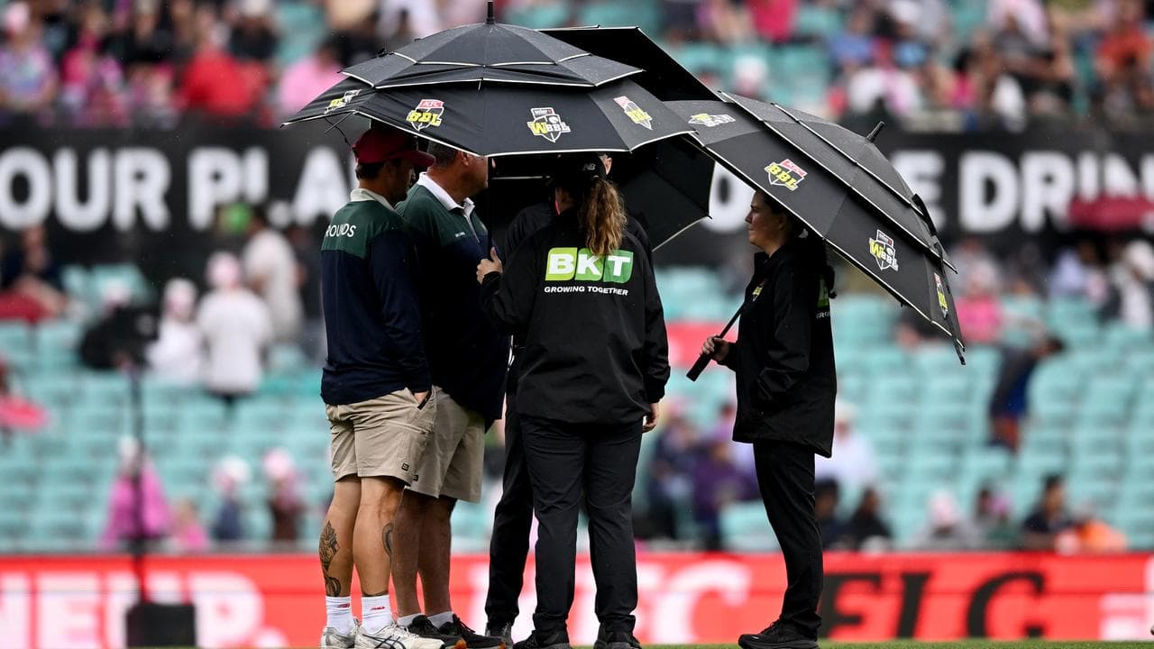 Umpires and ground staff inspect the field  at the SCG.