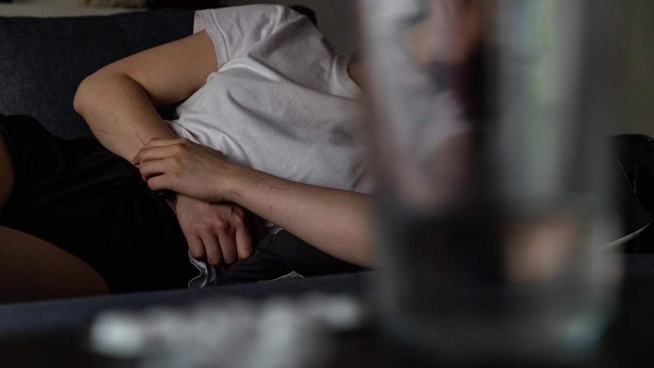 A person holds their stomach as they lie on the couch