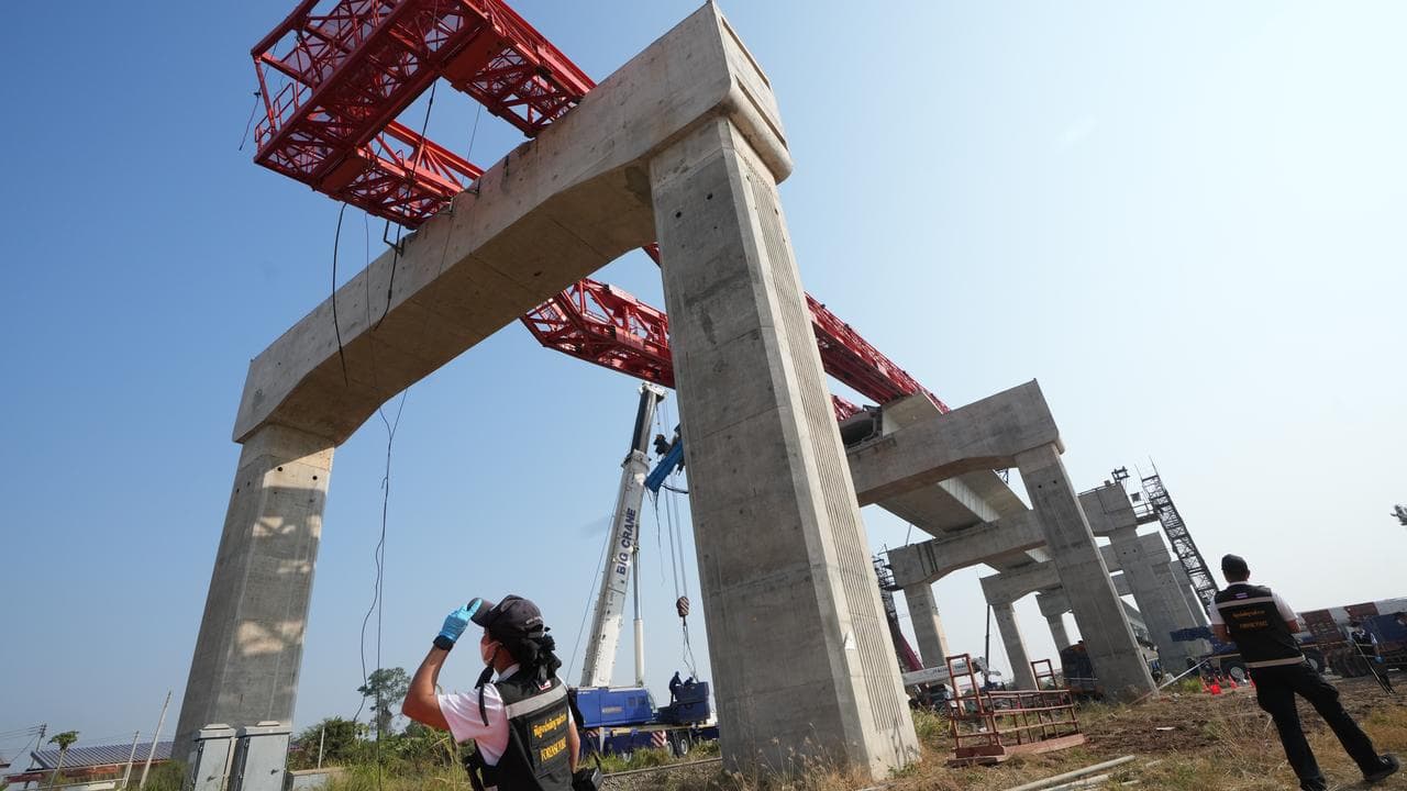 Forensic workers inspect a crane and train accident site in Thailand