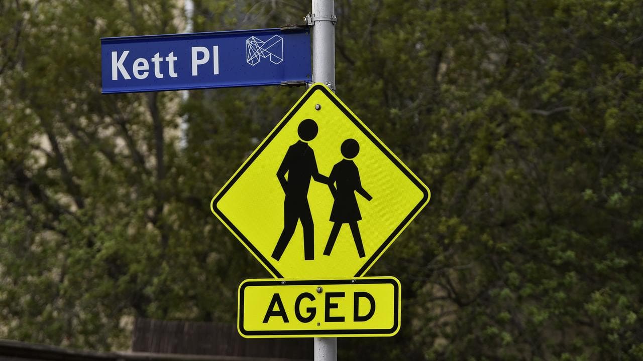 A hazard sign warning drivers of elderly members crossing the street.