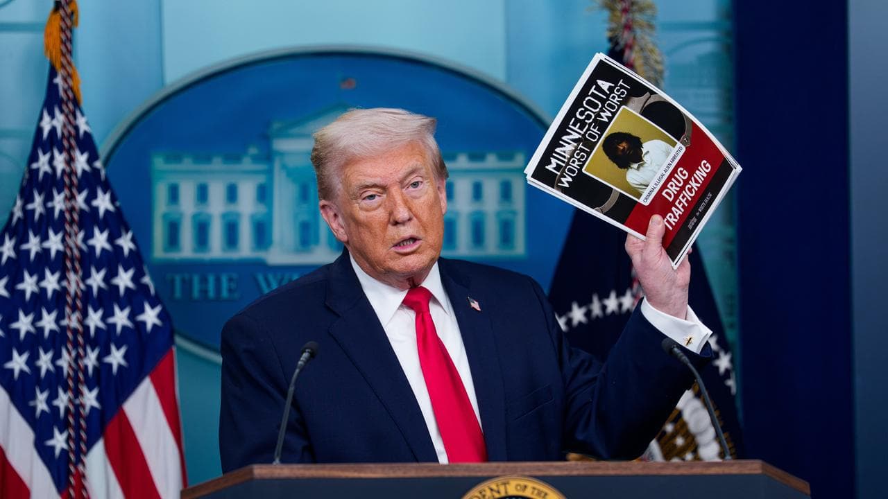 Donald J. Trump holds a photo of an alleged individual in Minnesota