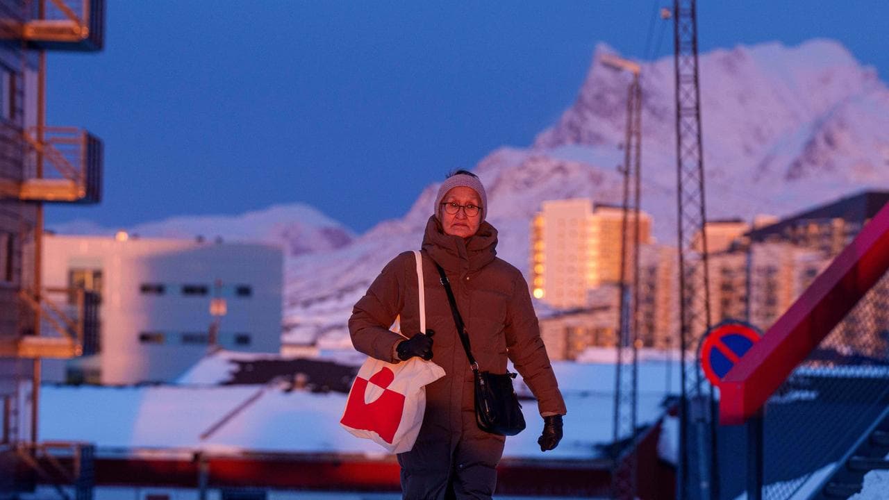 A woman walks on a street at sunset in Nuuk, Greenland