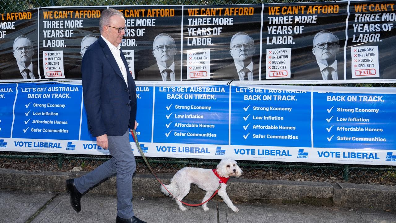 Anthony Albanese walks past coalition posters