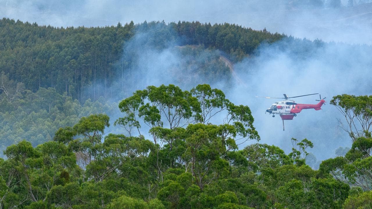 A fire fighting aircraft flies through smoke