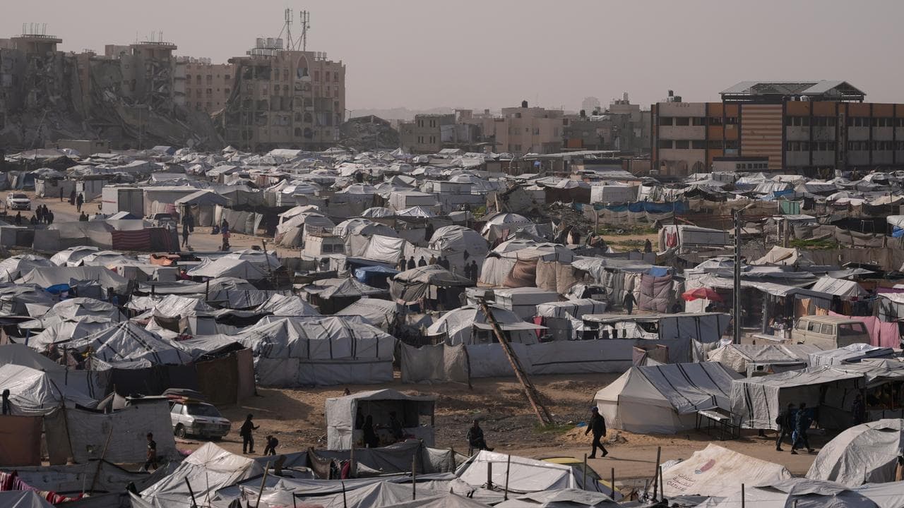 Palestinians walk along tents at a makeshift camp