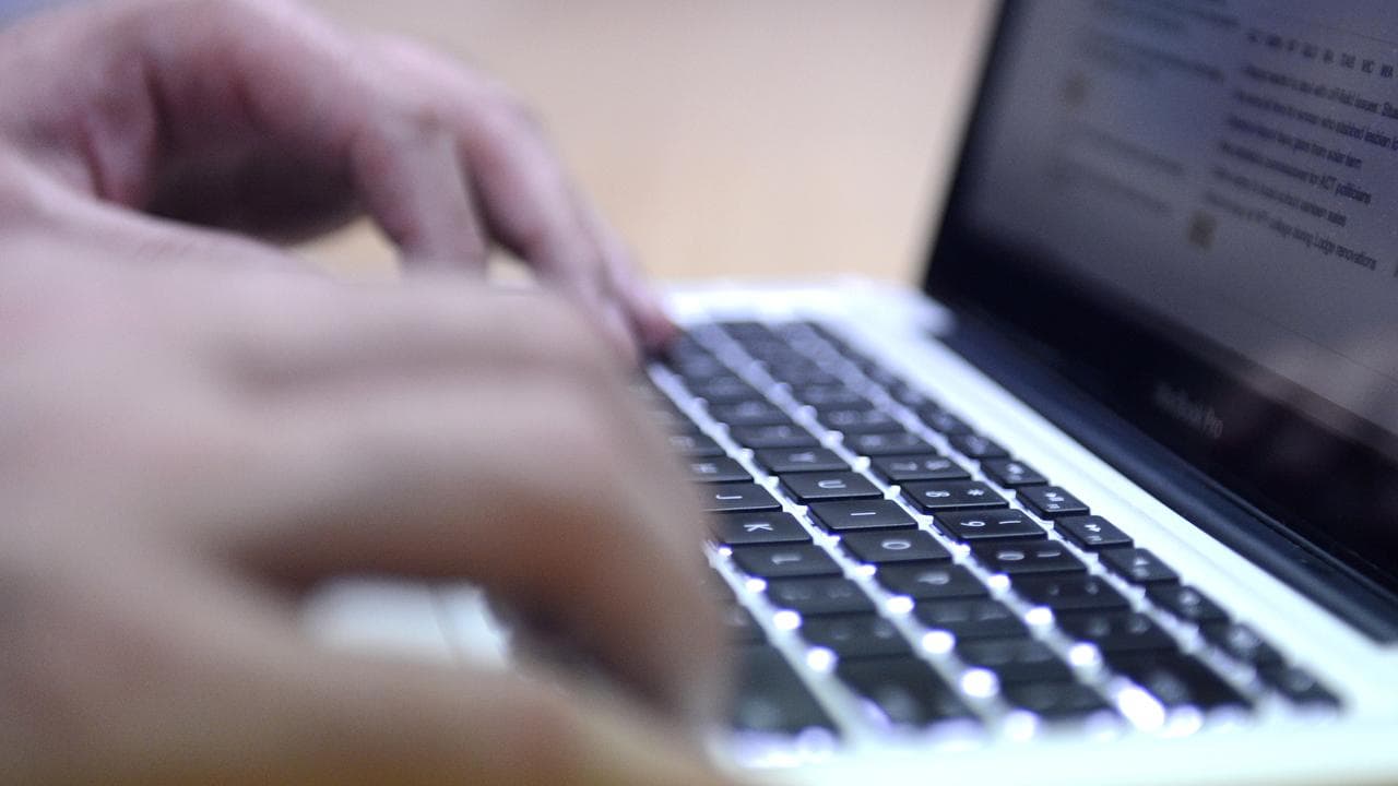 A pair of hands typing on a laptop