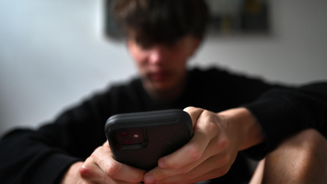 A teenager uses his mobile phone