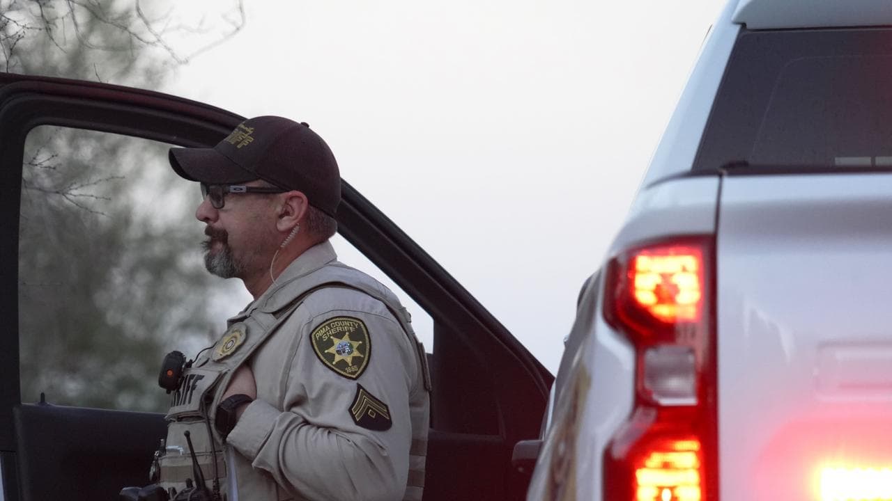 A policeman stands by his truck looking at Nancy Guthrie‘s house