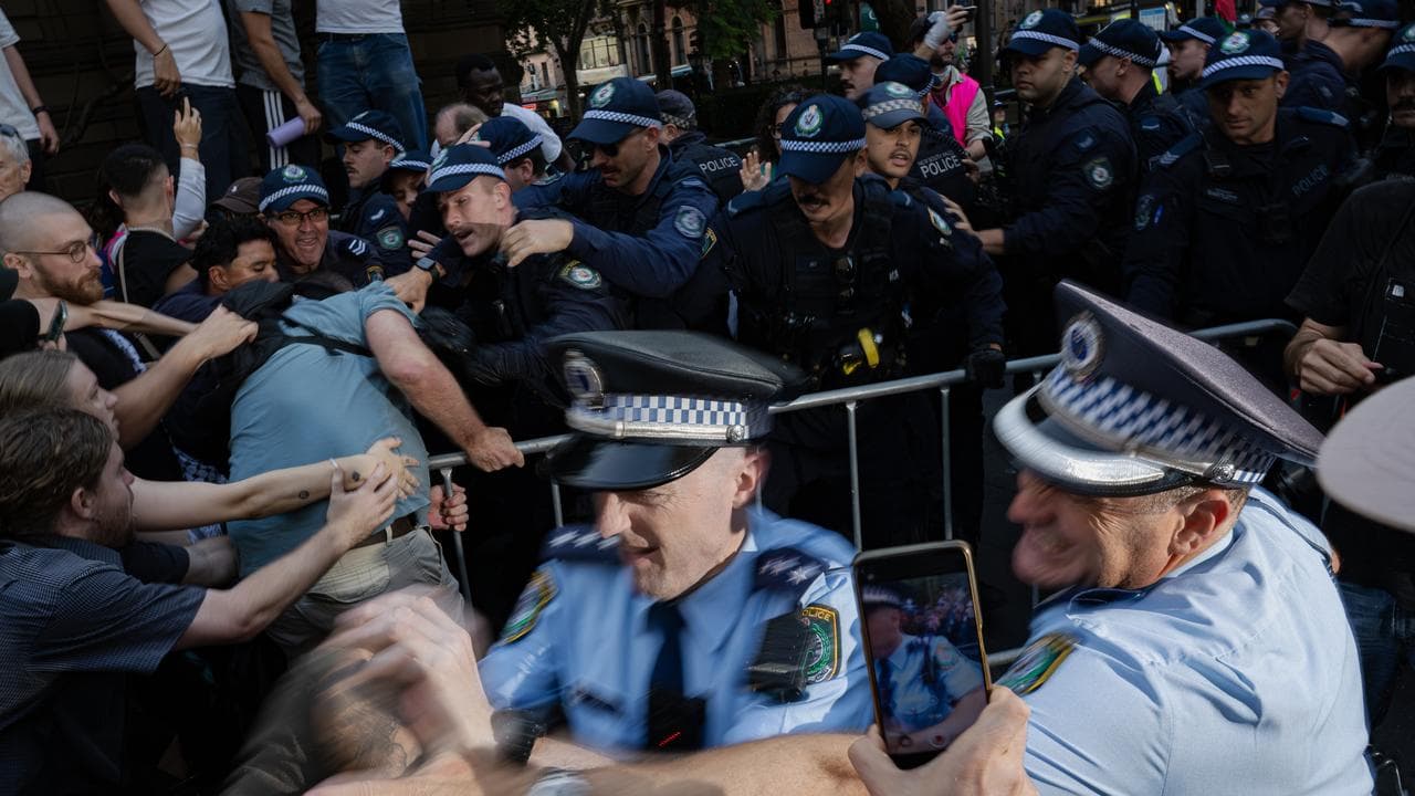 Police officers detain demonstrators during a protest