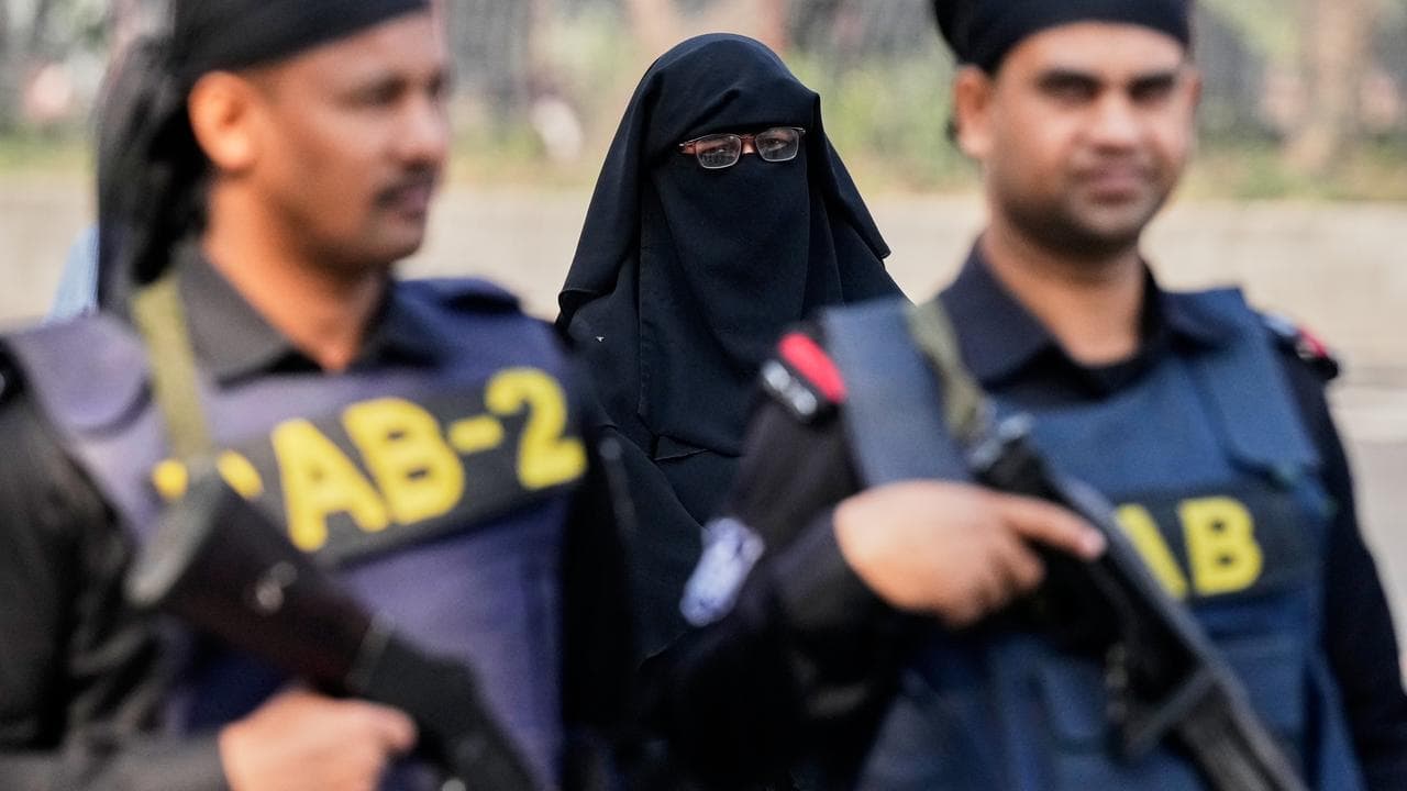 A Bangladeshi woman arrives to vote as security personnel stand guard