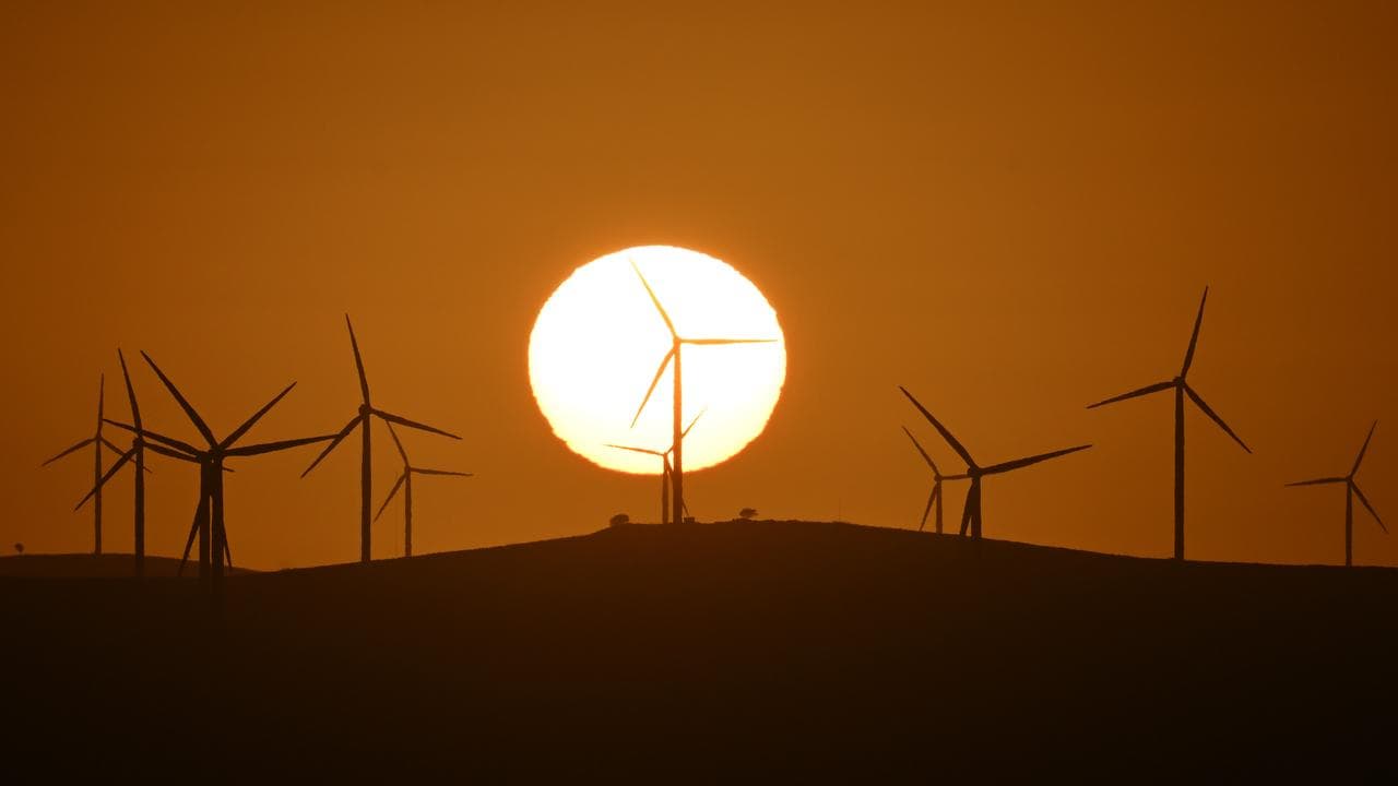 The sun rises over power-generating wind turbines