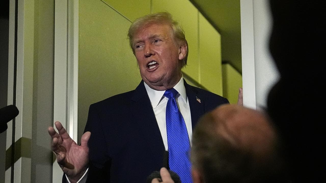 US President Donald Trump speaks with reporters aboard Air Force One