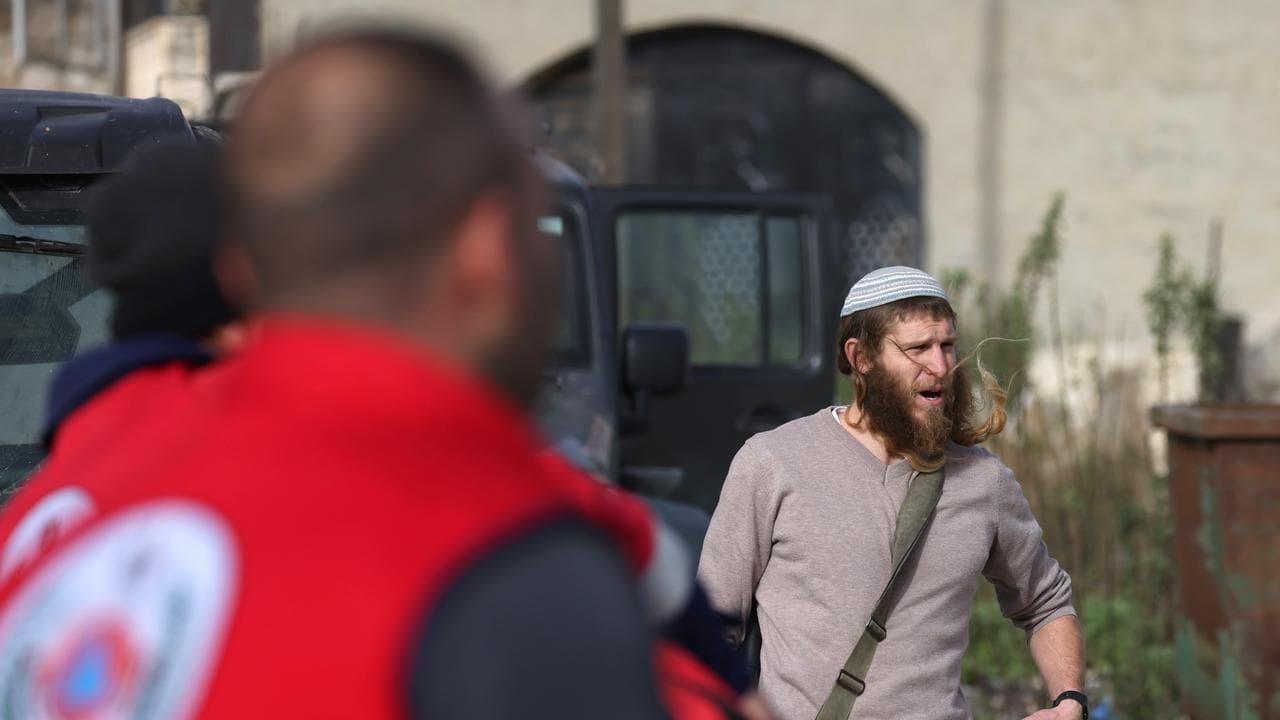 An Israeli settler confronts Palestinian medical workers