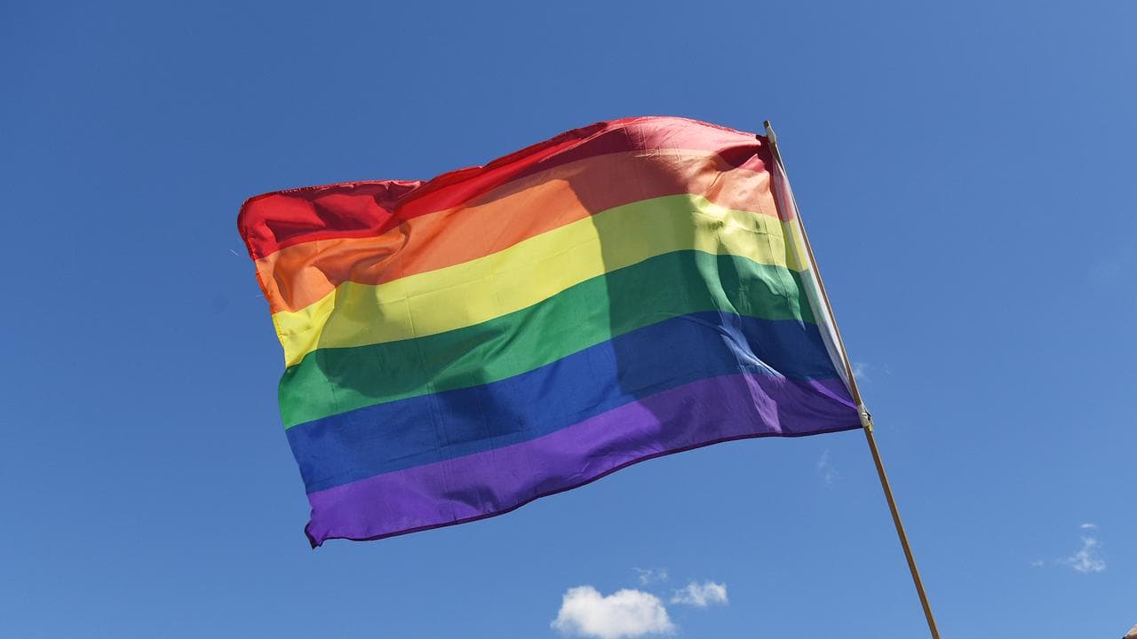 A man holds a rainbow flag