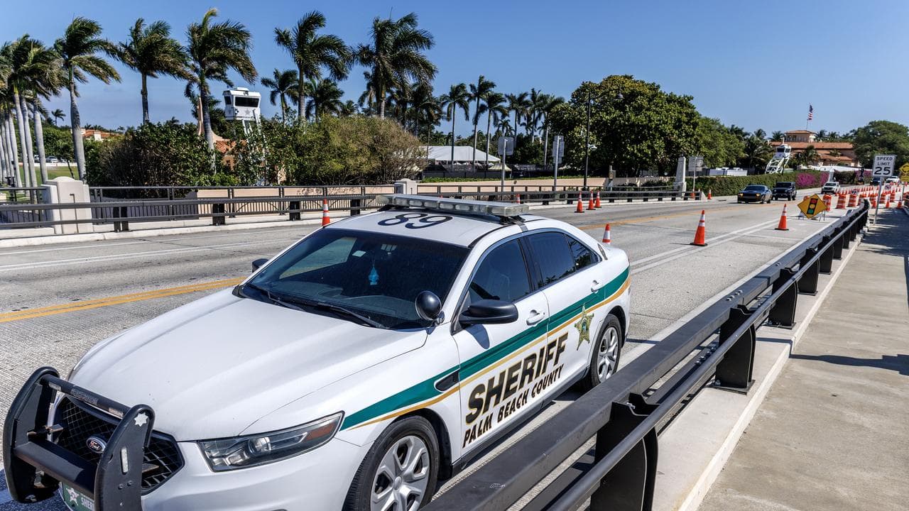 A Sheriff vehicle patrols a road block near the Mar-a-Lago club