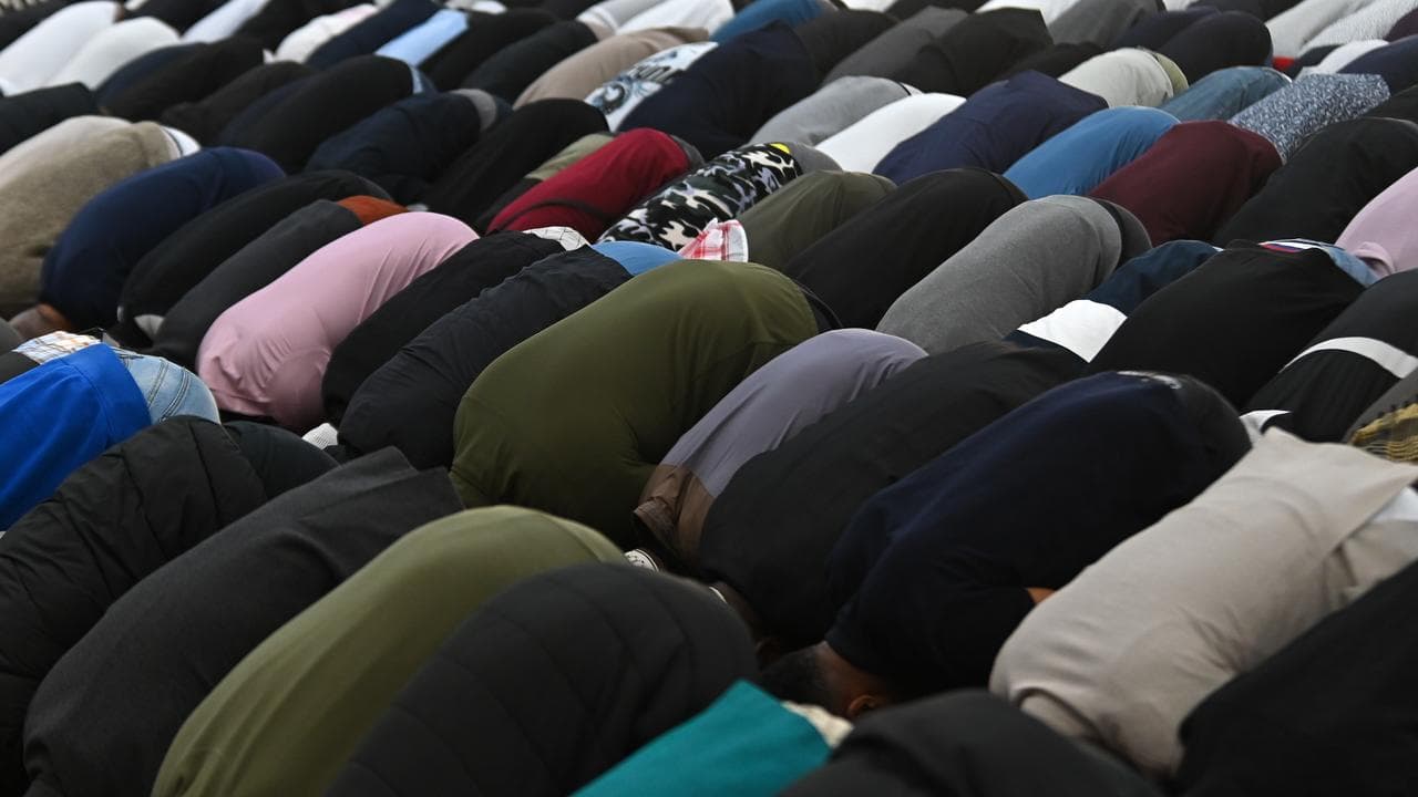 A line of people praying at a mosque.