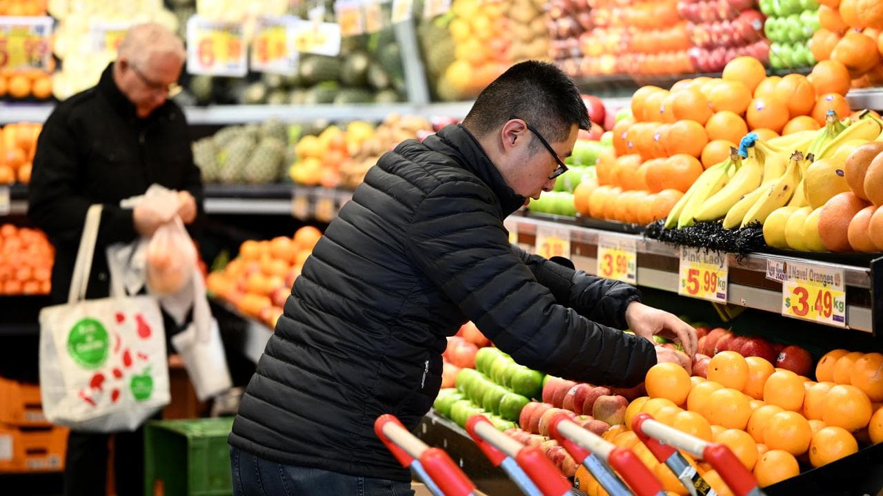 A worker arranges apples for sale at a market in Melbourne