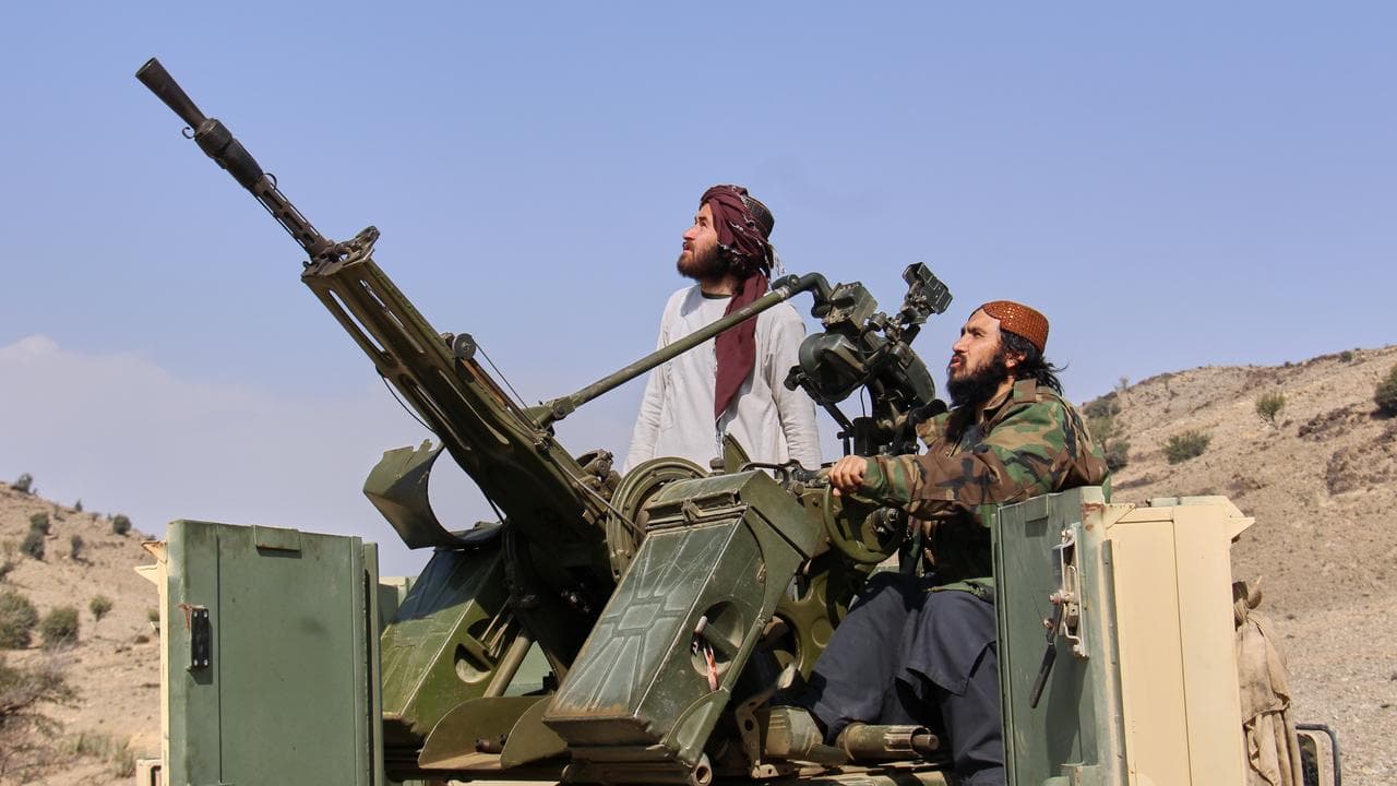Taliban fighters look up while manning an armed pick-up truck