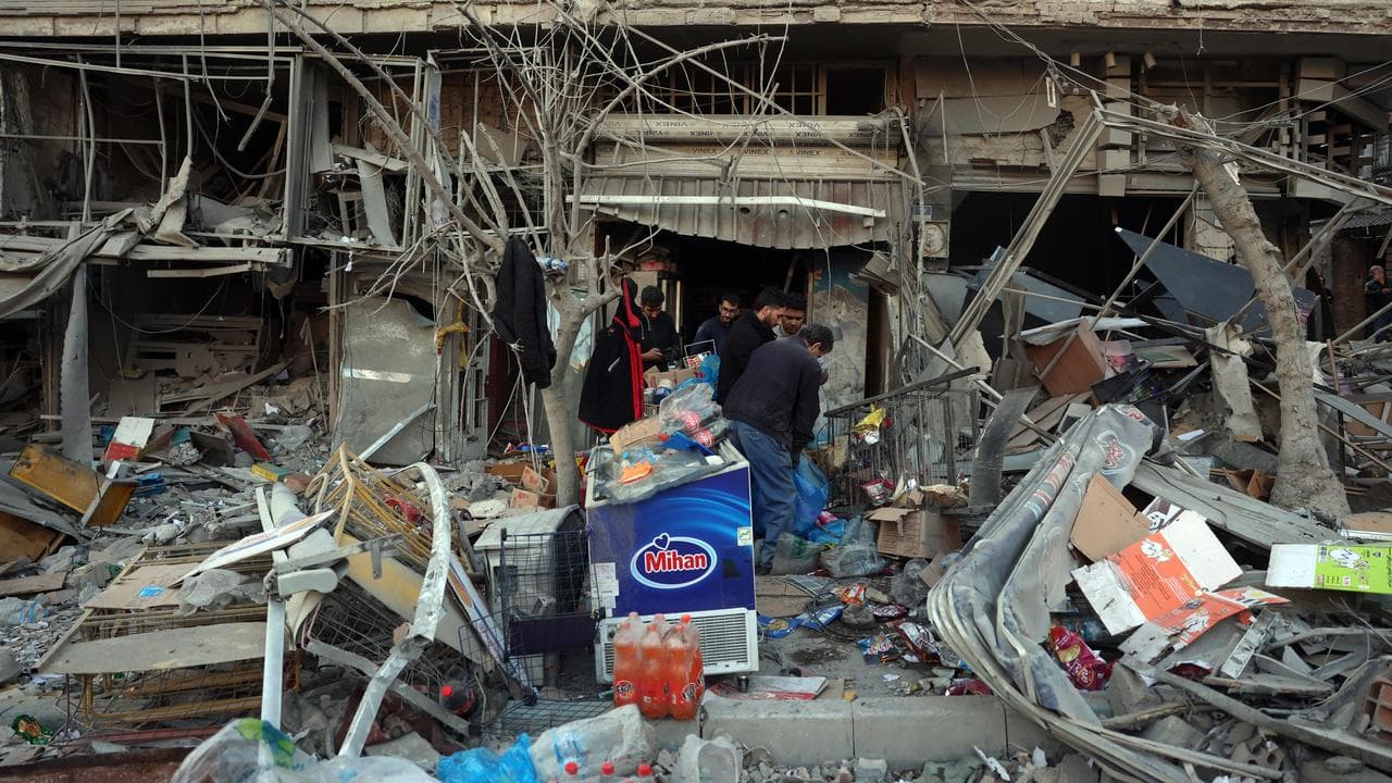 Iranians inspect a damaged shop