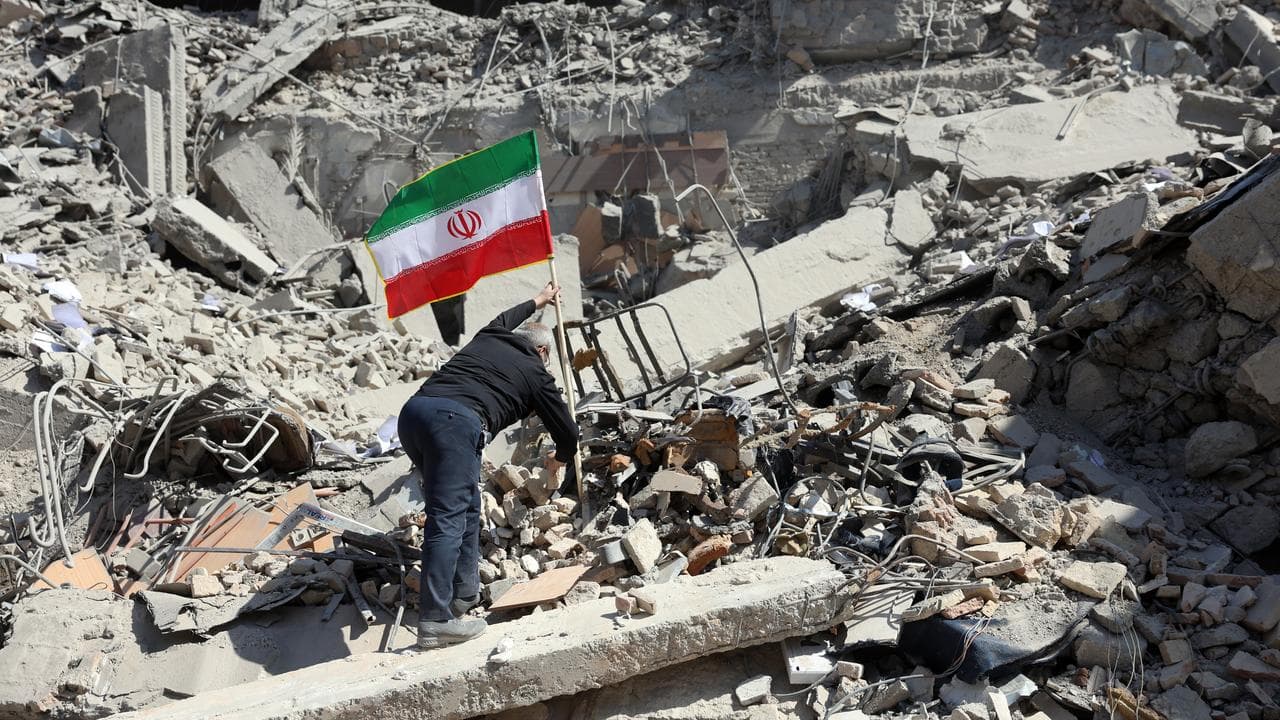 A man places Iran's national flag among the ruins