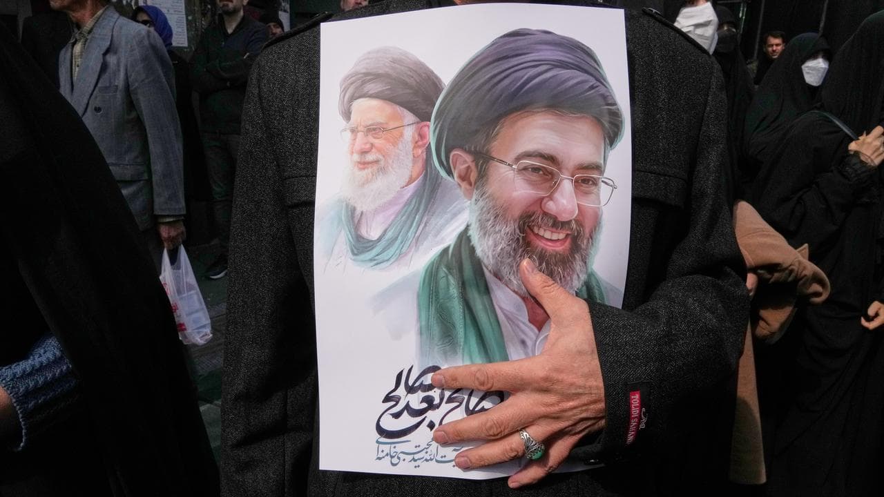 A mourner holds a poster depicting Ayatollah Mojtaba Khamenei