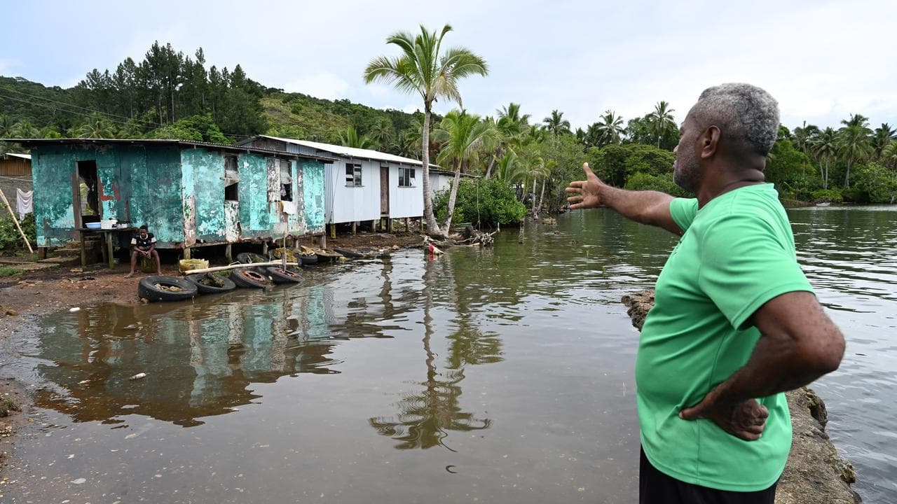 A Fijian man points to damage caused by rising sea levels.