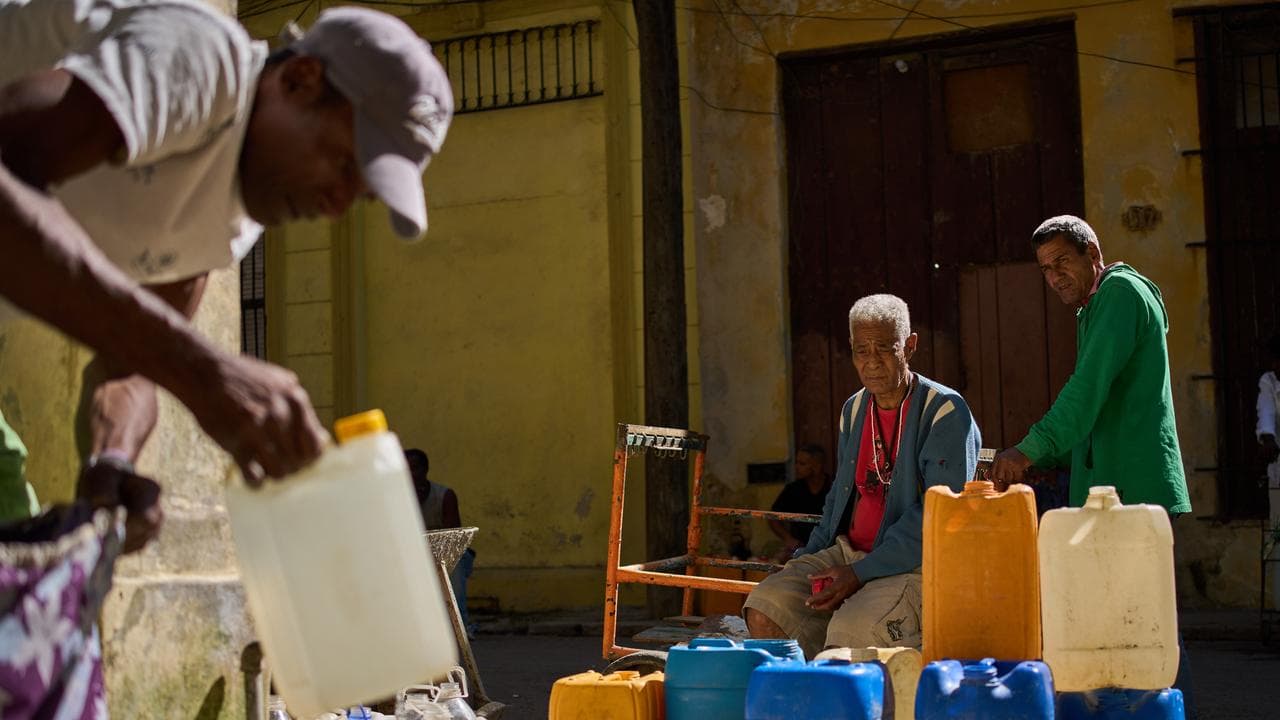 A man fill containers with potable water during a blackout in Havana