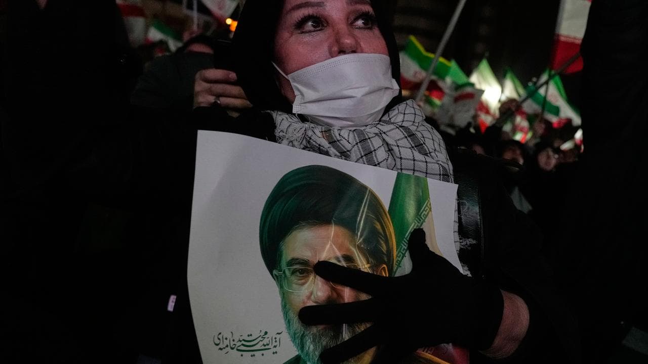 A woman holds a picture of the Ayatollah Mojtaba Khamenei