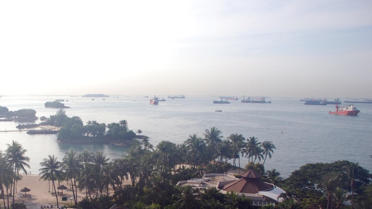 A photo of a resort in Singapore with oil tankers in the background.