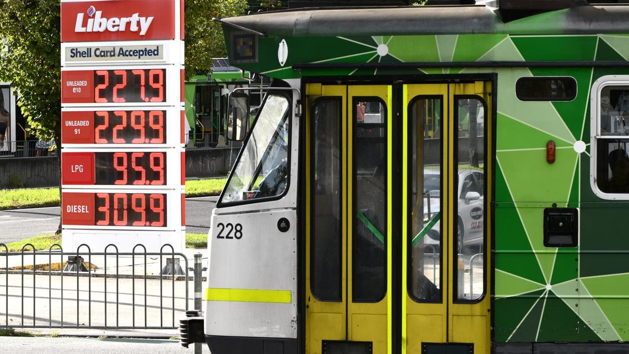 A tram passes signage showing fuel prices