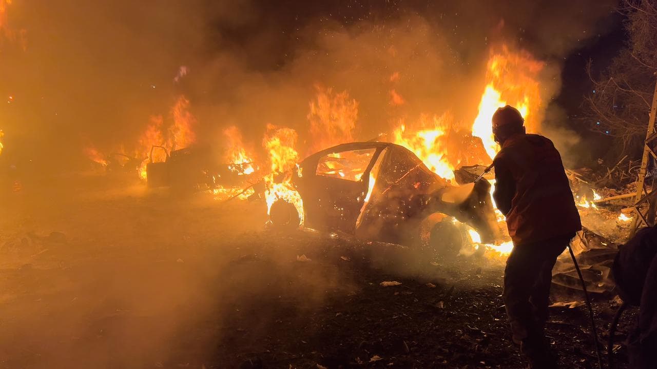 A firefighter extinguishes a car after an Israeli air strike in Beirut