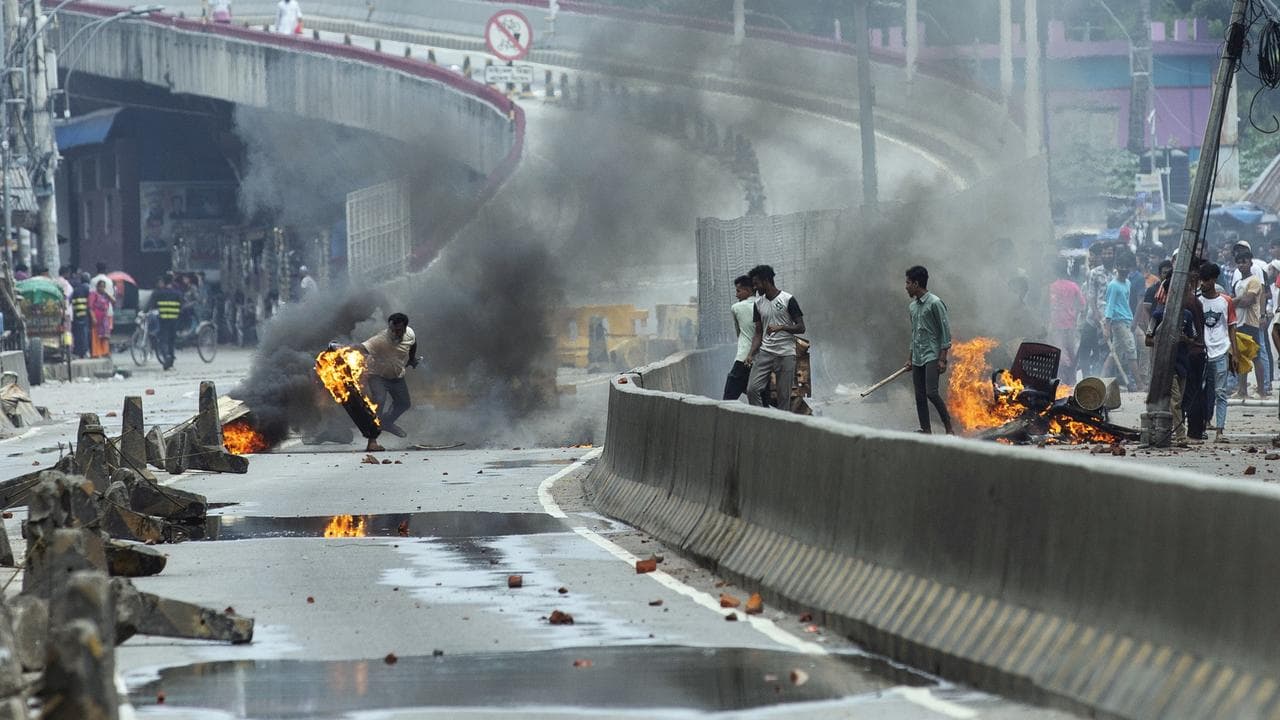 A Bangladeshi protester throws a rubber tire on fire