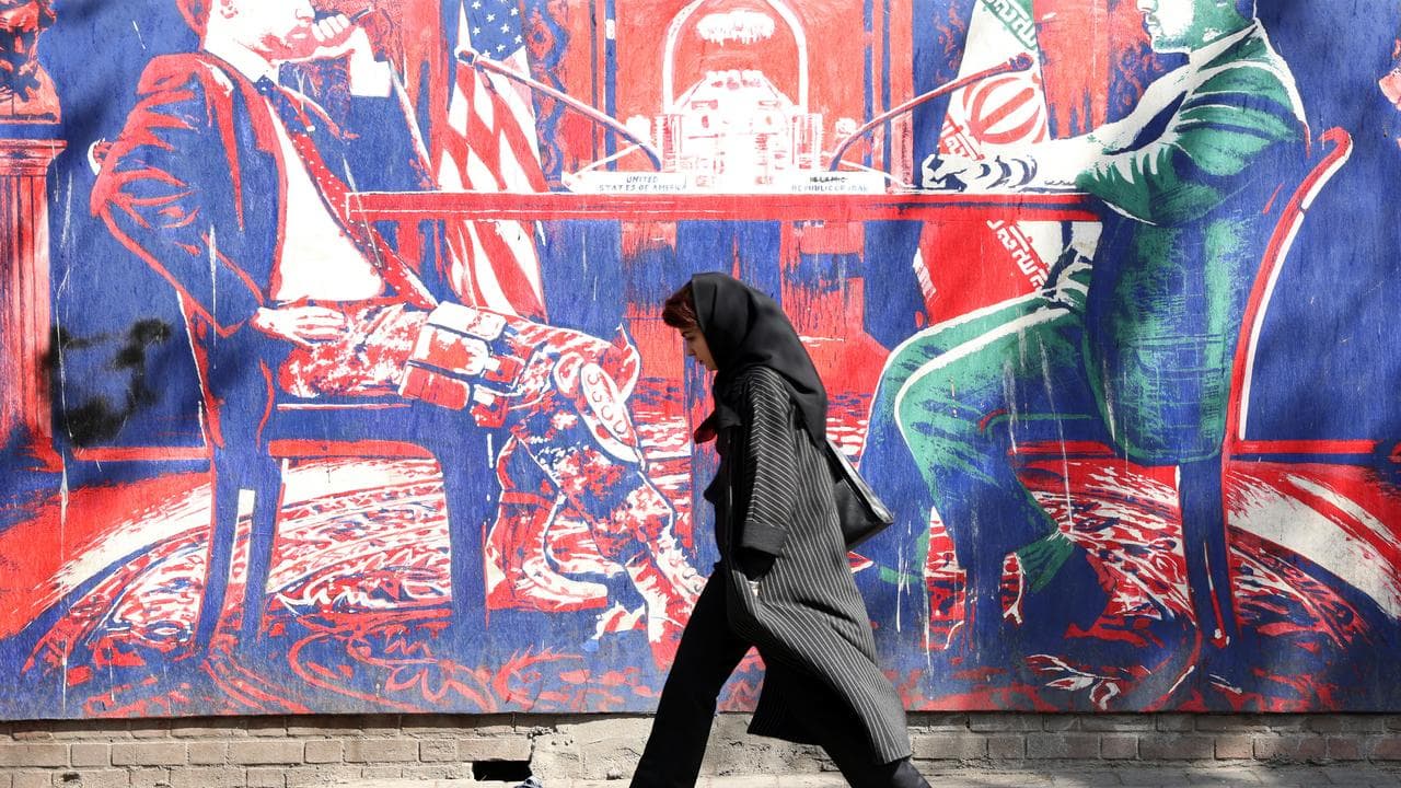 A woman walks past an anti-US mural in Tehran