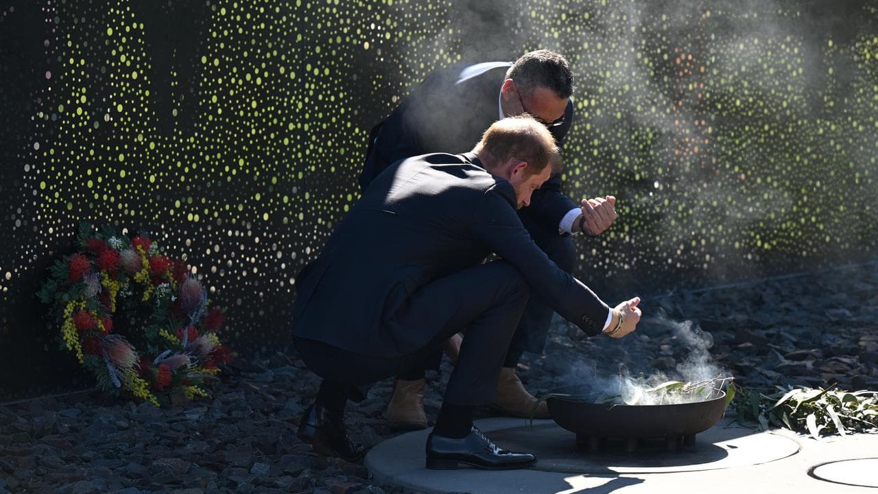 Prince Harry Crouches in front of fire 