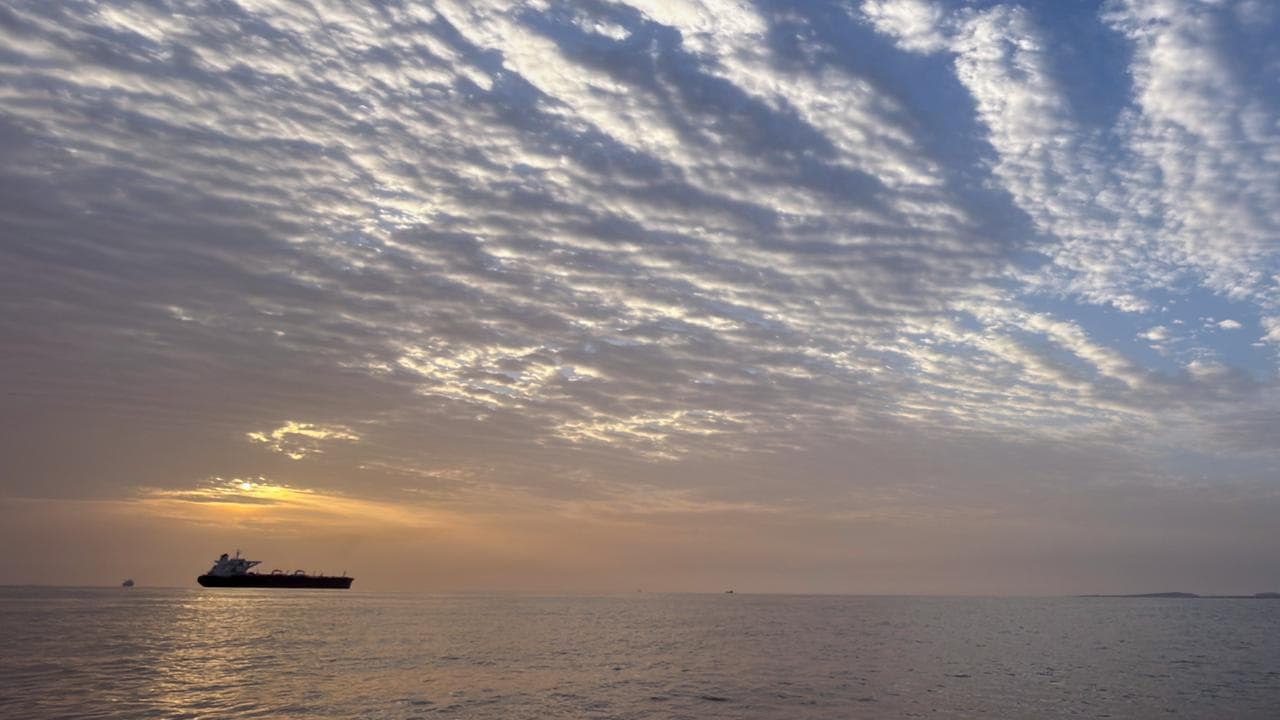 The sun rises behind a tanker anchored in the Strait of Hormuz