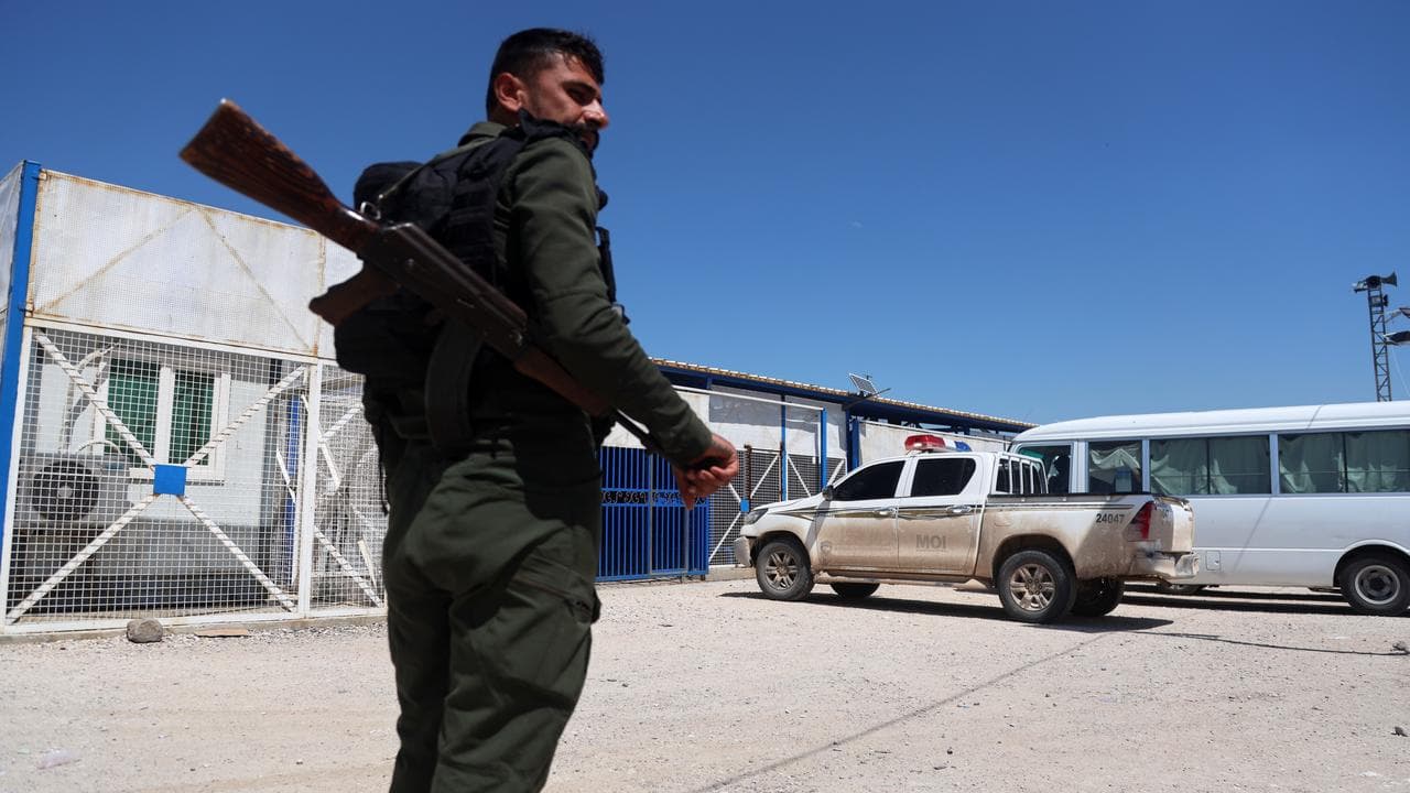 A soldier stands guard as vehicles arrive at Roj Camp