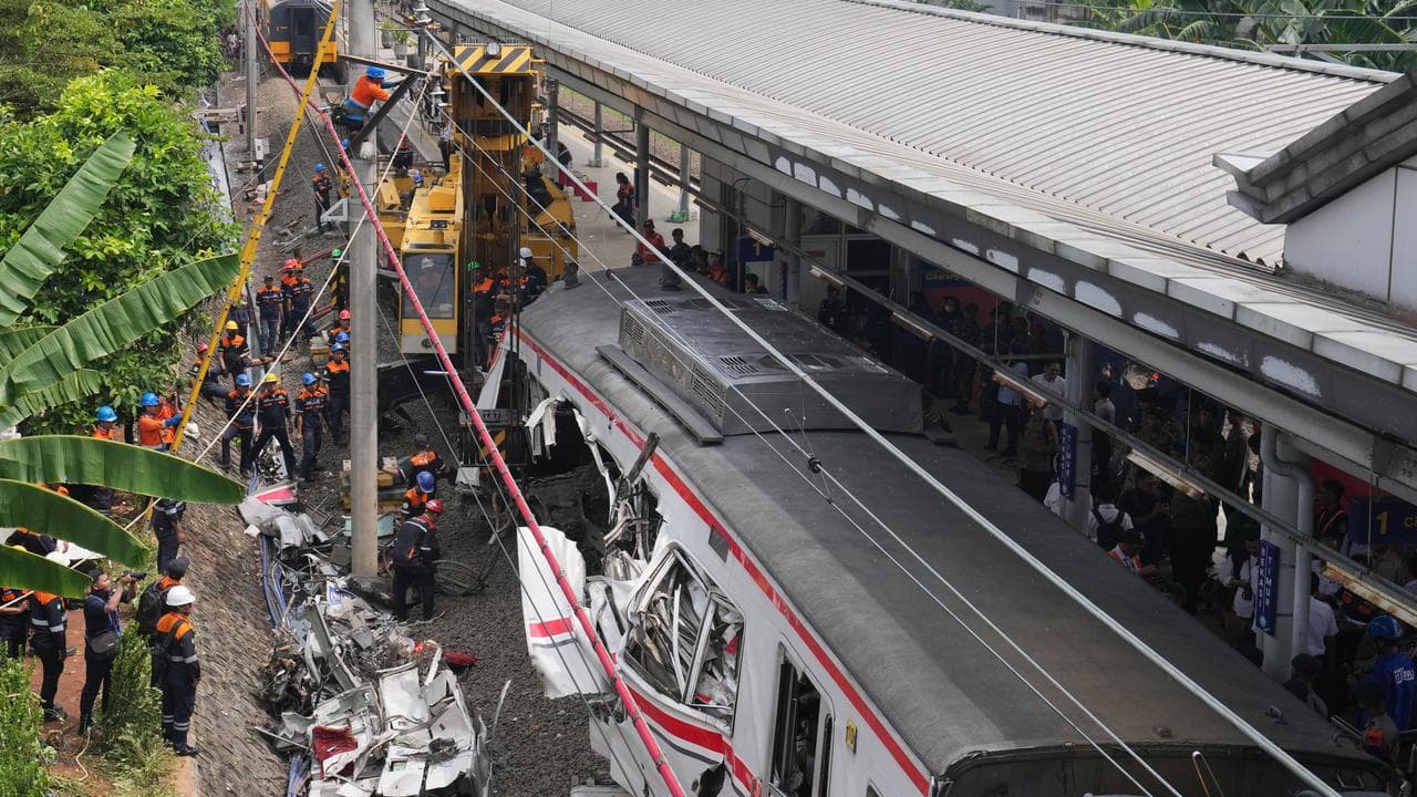 A heavy machine removes train wreckage after a collision in Indonesia